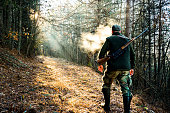 Hunter with rifle walking in the forest