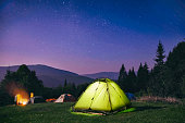 Illuminated  green  tent under stars at night  forest