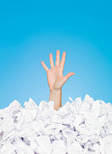 Image of person buried in paper leaving one hand out