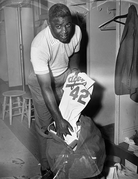 In this prophetic photo, previously unserviced Jackie Robinson packs away his Dodger uniform, with the number 42 which he made famous, after the...
