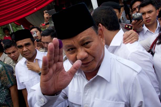 Indonesian presidential candidate Prabowo Subianto waves with an inkstained finger after voting in his local polling station on July 9 2014 in Bojong...