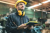 Industrial Engineers in Hard Hats.Work at the Heavy Industry Manufacturing Factory.industrial worker indoors in factory. man working in an industrial factory.Safety first concept.