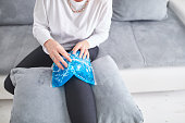 Injured woman holding ice pack / bag for cooling down the knee pain.