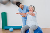 Instructor assisting senior woman in exercising