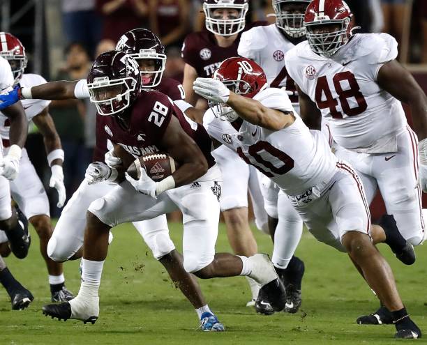 Isaiah Spiller of the Texas A&M Aggies rushes past Henry To'oTo'o of the Alabama Crimson Tide in the first half at Kyle Field on October 09, 2021 in...