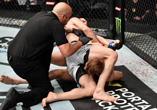 Islam Makhachev of Russia secures an arm lock submission against Dan Hooker of New Zealand in a lightweight fight during the UFC 267 event at Etihad...