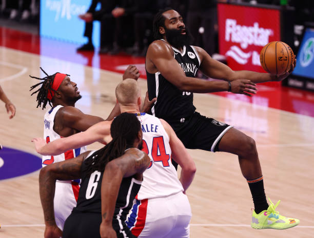 James Harden of the Brooklyn Nets drives around Mason Plumlee and Jerami Grant of the Detroit Pistons during the first half at Little Caesars Arena...
