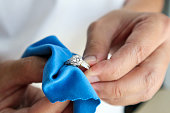 Jeweller hand polishing and cleaning jewelry diamond ring with micro fiber fabric