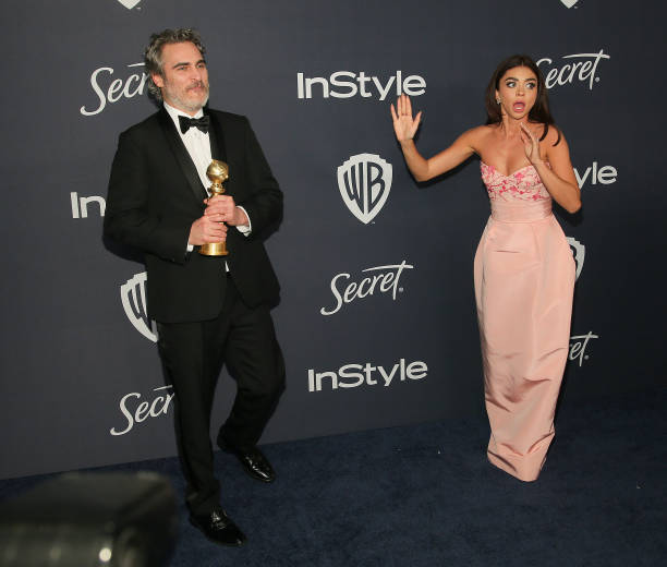 Joaquin Phoenix is applauded by actress Sarah Hyland as he poses for a photo with his award for Best Performance by an Actor in a Motion Picture...