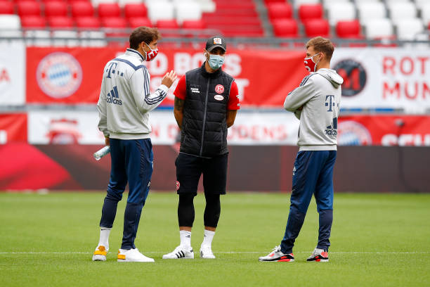 Joshua Kimmich and Leon Goretzka of FC Bayern Muenchen wear face masks as they talk to a player of Fortuna Duesseldorf prior to the Bundesliga match...