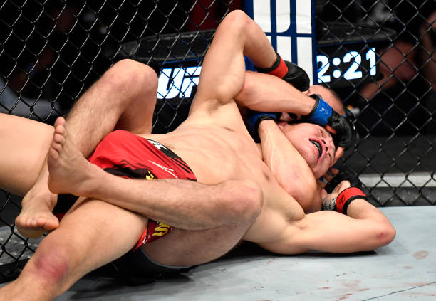 Khamzat Chimaev of Sweden secures a rear choke submission against Li Jingliang of China in a welterweight fight during the UFC 267 event at Etihad...