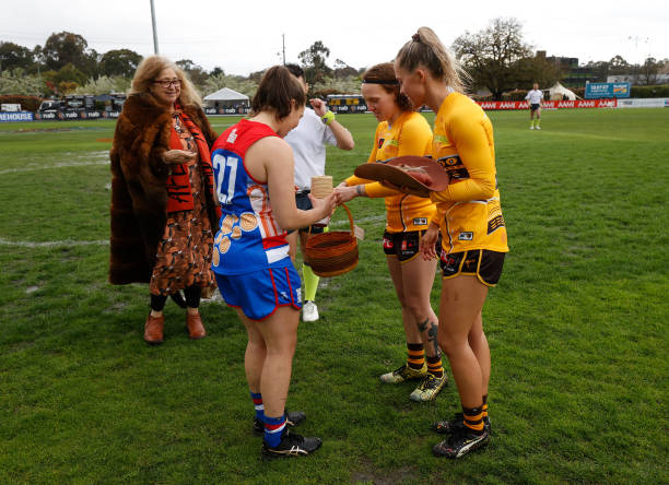 Kirsty Lamb of the Bulldogs and Tilly Lucas-Rodd and Kaitlyn Ashmore of the Hawks exchange gifts during the 2022 S7 AFLW Round 04 match between the...