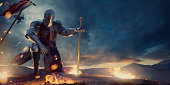 Knight in Amour Kneeling With Sword on Hilltop Near Fire