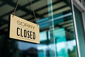 Label 'Sorry we are closed please come back again' notice sign wood board hanging on door front coffee shop.