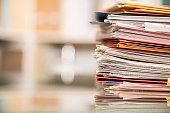 Large stack of files, documents, paperwork on desk.