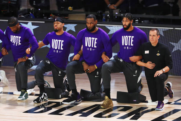 LeBron James of the Los Angeles Lakers and Anthony Davis of the Los Angeles Lakers and Frank Vogel of the Los Angeles Lakers kneel during the...