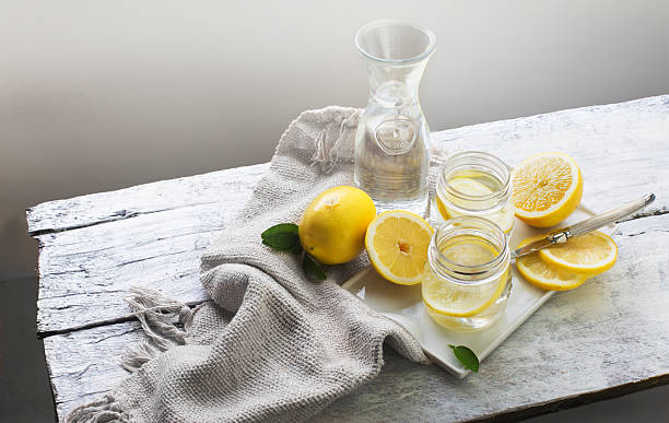 lemon water on white wooden table. still life. - lemon stock pictures, royalty-free photos & images
