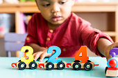 Little boy playing mathematics wooden toy at nursery