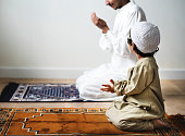 Little boy praying alongside his father during Ramadan