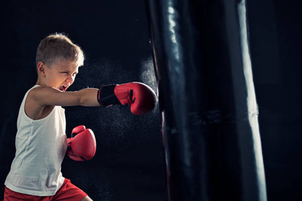 Little boy del boxeo entrenamiento con saco de boxeo
