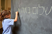 Little girl writes Hello First Grade greetings in Hebrew