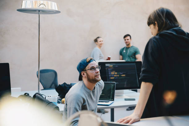 male and female computer programmers discussing in creative office - professional software developer stock pictures, royalty-free photos & images