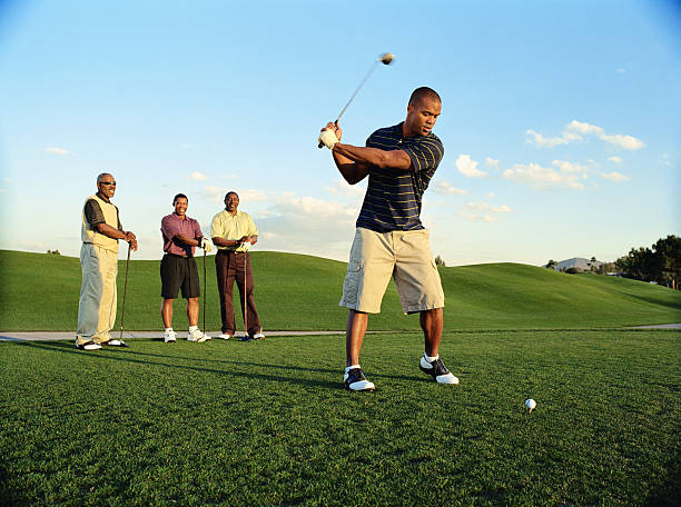 male golfer driving ball, friends watching (blurred motion) - golfeur photos et images de collection