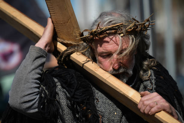 Man acting as Jesus and carrying a cross seen during a Solemn Procession on Good Friday 2021, walking and praying from the General Post Office to the...