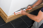 Man caulking wooden skirting in a new property