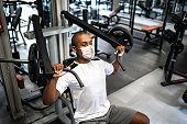 Man doing strength workout exercise in gym with face mask