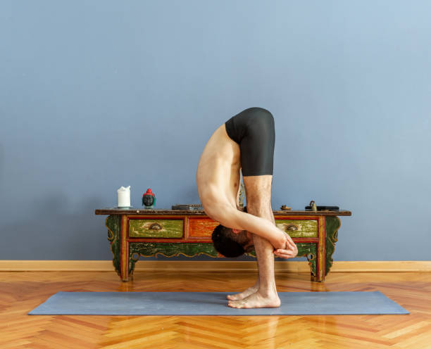 man doing uttanasana pose in yoga - forward fold (uttanasana) stock pictures, royalty-free photos & images