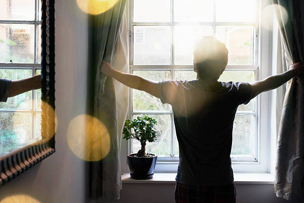 man opening curtains in the morning - morning stock pictures, royalty-free photos & images