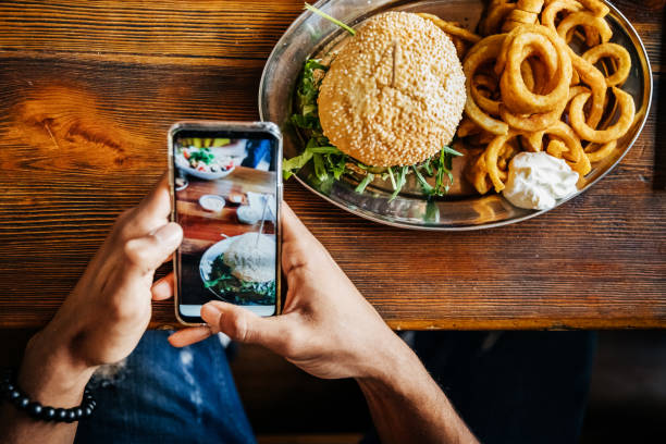 man talking picture of burger with smartphone picture