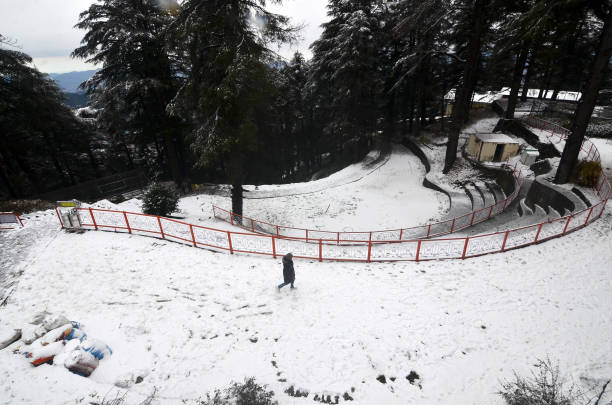 Man walks on the snow covered road after the seasons first snowfall at Jakhoo on January 8, 2022 in Shimla, India.