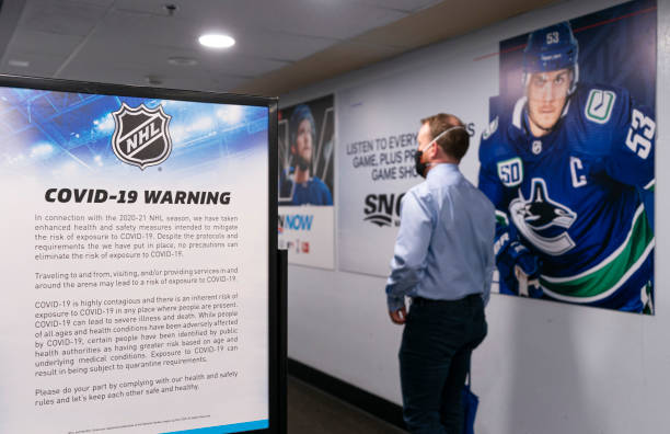 Man walks past a COVID-19 warning sign after entering Rogers Arena prior to NHL hockey action between the Vancouver Canucks and the Toronto Maple...