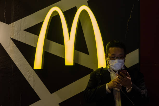 man wearing a face mask checks his smartphone next to a mcdonalds at picture