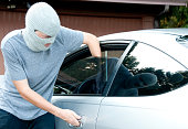 Masked teenager breaking into a car