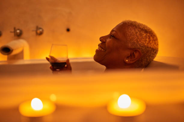 mature woman relaxes in bath - self care stock pictures, royalty-free photos & images