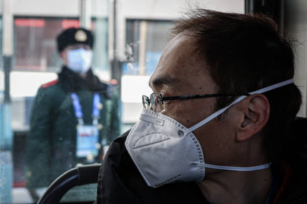 Member of the People's Liberation Army stands on patrol outside a building, as a member of the media travels on a bus in a closed-loop bubble on...