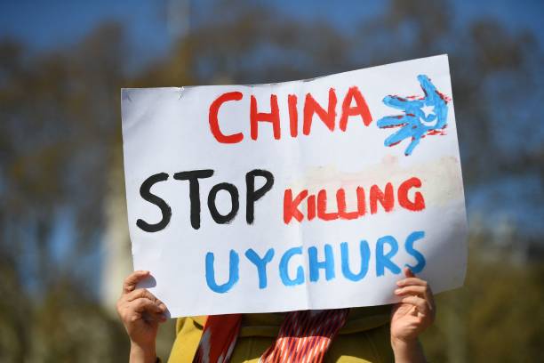 Member of the Uyghur community holds a placard as she joins a demonstration to call on the British parliament to vote to recognise alleged...