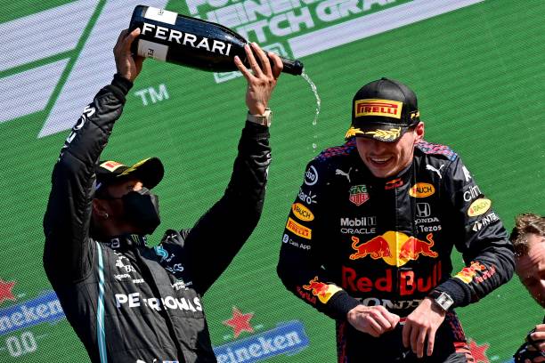 Mercedes' second placed British driver Lewis Hamilton and winner, Red Bull's Dutch driver Max Verstappen , celebrate on the podium of the Zandvoort...