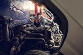 Mid adult mechanic repairing a truck in auto repair shop.