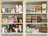 A middle-aged woman tidies up her cupboard in the kitchen and reorganizes everything