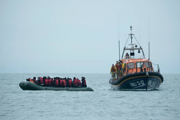 Migrants are helped by RNLI lifeboat
                          before being taken to a beach in Dungeness, on
                          the south-east coast of England, on November
                          24 after crossing...