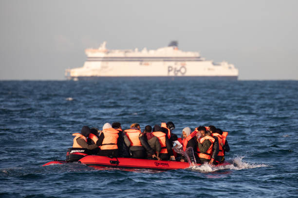 Migrants packed tightly onto a small
                          inflatable boat bail water out as they attempt
                          to cross the English Channel near the Dover
                          Strait, the world's...