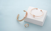 Modern golden bracelets and ring on white and blue background with copy space