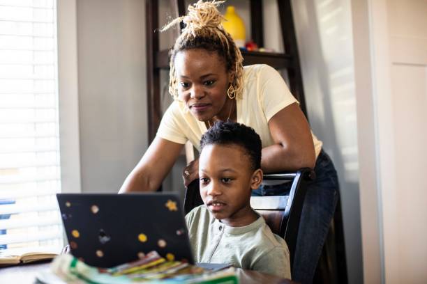 mother helping son during e-learning at home - aula online - fotografias e filmes do acervo
