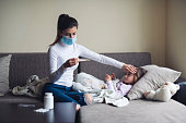 A Mother Measure Temperature On Her Sick Child At Home.