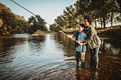 Mother teaching her son how to catch a fish