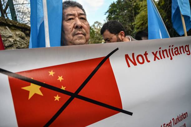 Muslim Uighur holds a banner as he waves a flag of East Turkestan on December 13, 2019 during a demostration in front of China Consulate in Istanbul....